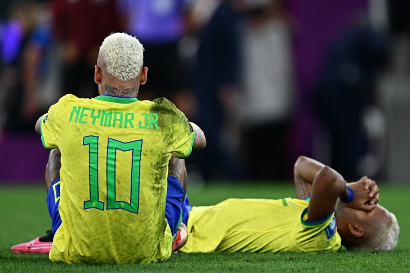 Neymar e outro jogador sentados na grama lamentando a derrota.